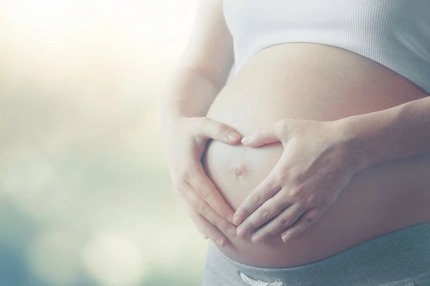 Kobieta w ciąży z dłońmi ułożonymi na brzuchu